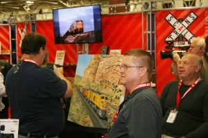 ScaleTrains.com President Shane Wilson (foreground) looks on as attendees record the company's debut. - Cowcatcher Magazine